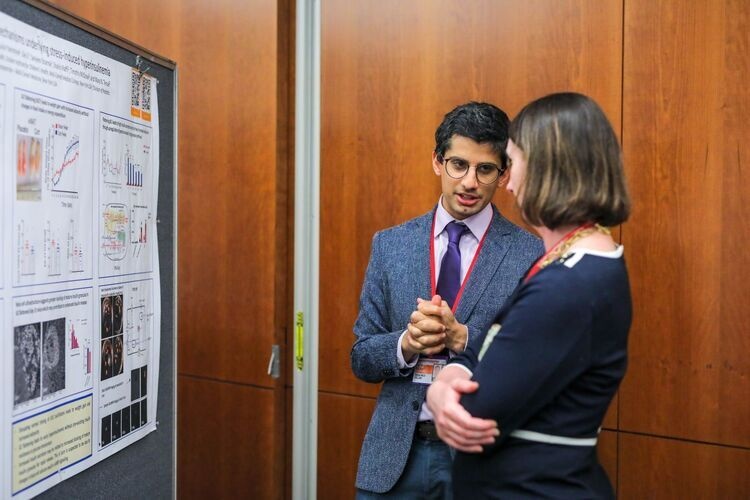 people speaking in front of a research poster